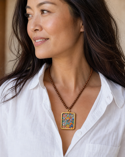 Woman wearing an AURESTAR Vaishravana thangka pendant with a white shirt.