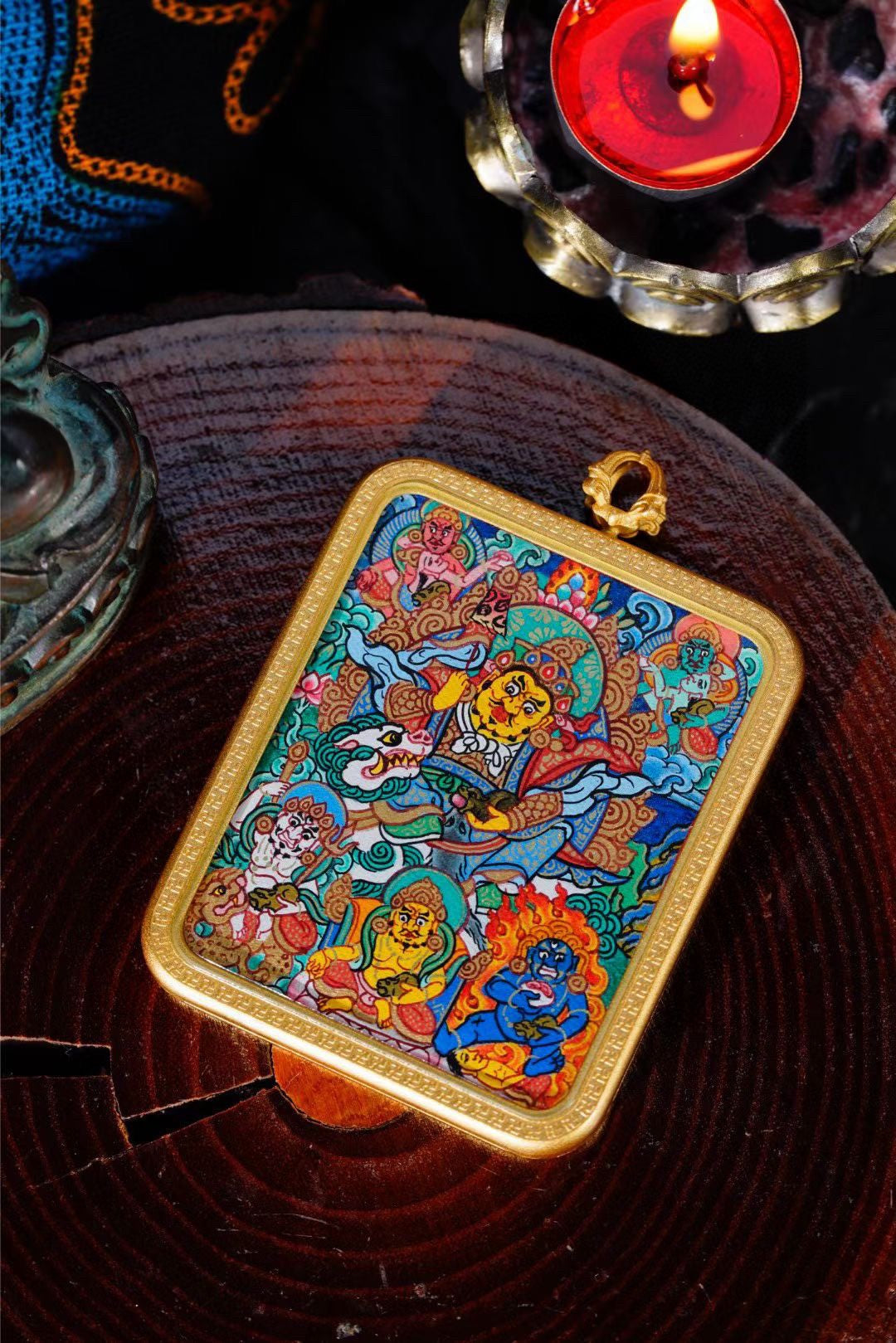 AURESTAR Vaishravana thangka pendant displayed on a dark wood tray.