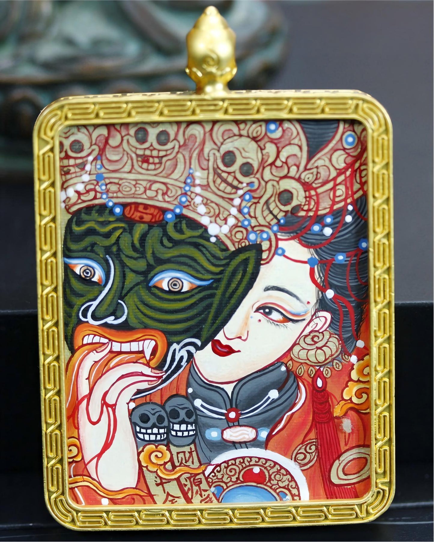 Close-up of a Zaki Lhamo thangka pendant in a gold-toned copper case.
